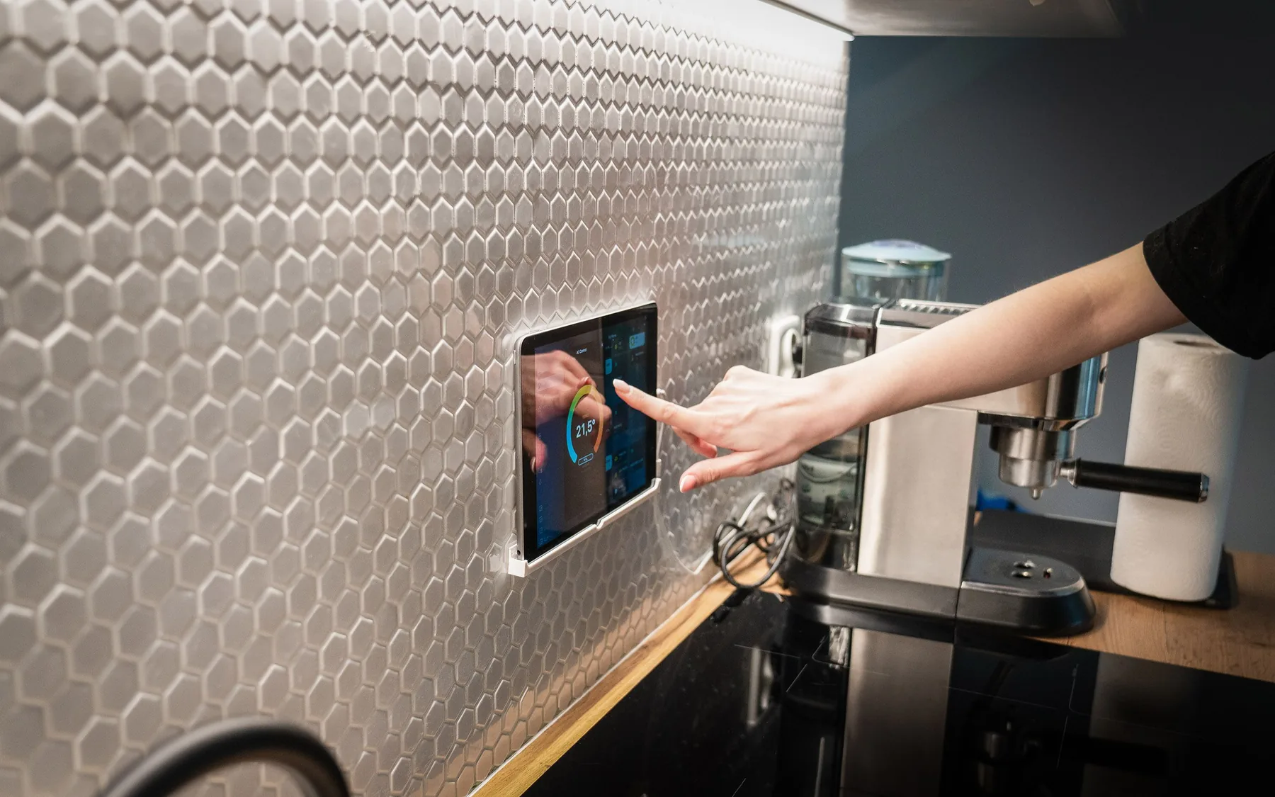 Panel táctil de domótica en la pared de una cocina, controlando climatización e iluminación